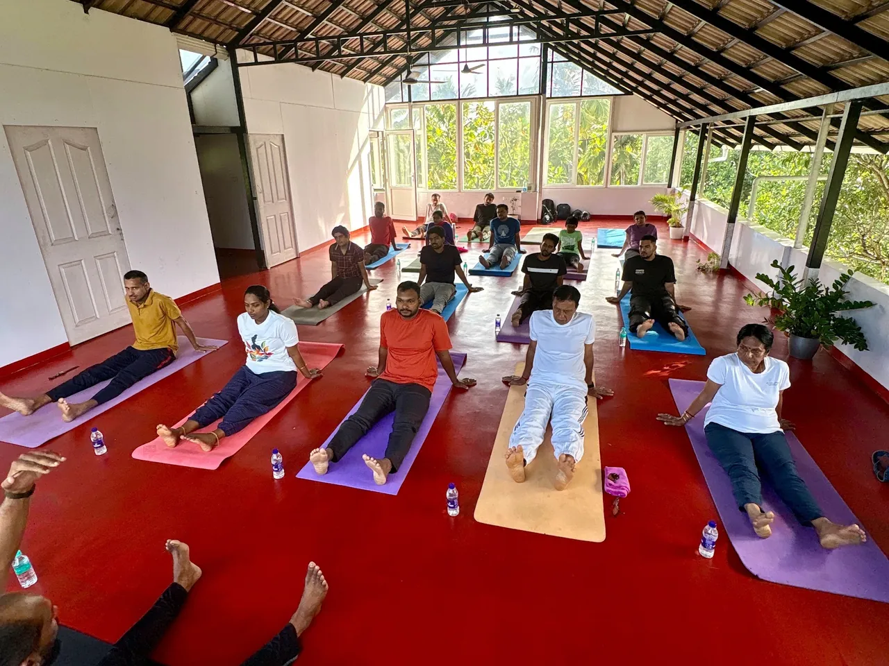 A morning class in the open sided studio at Kovalam, students seated on their mats under the tiled roof.