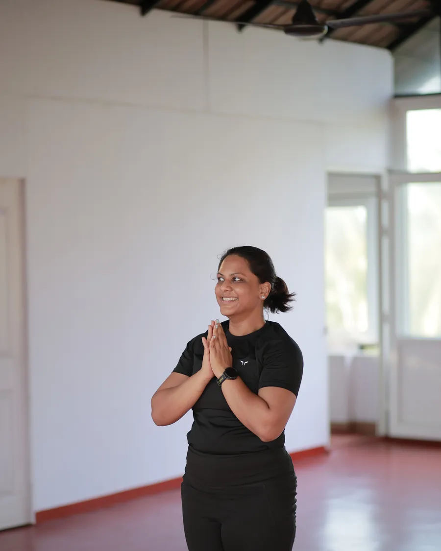 A student standing with her palms together at the end of a session in the studio at Kovalam.