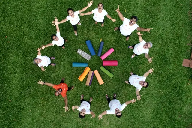 Students lying in a radiating circle on a lawn, photographed from above.