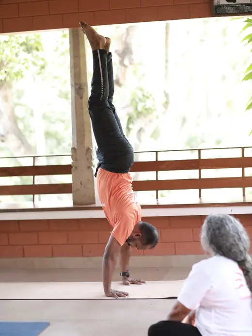A handstand held against the frame of the open-sided studio.