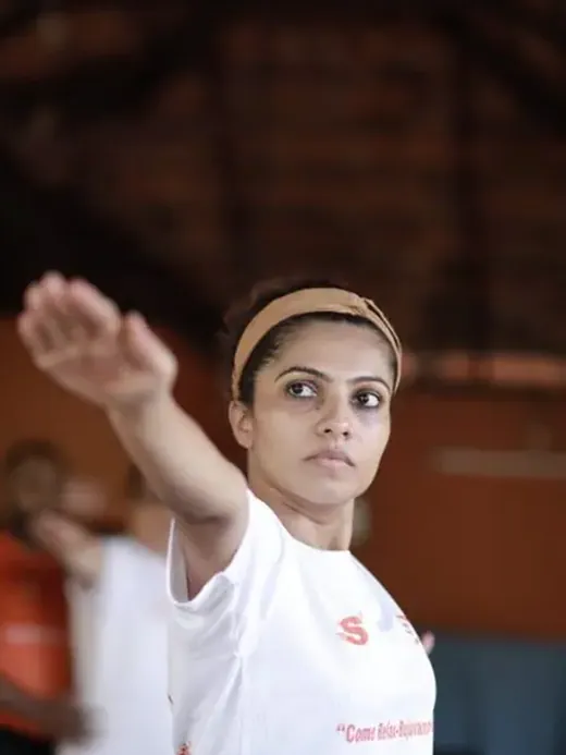 A student in class at Kovalam, one arm extended, photographed close.
