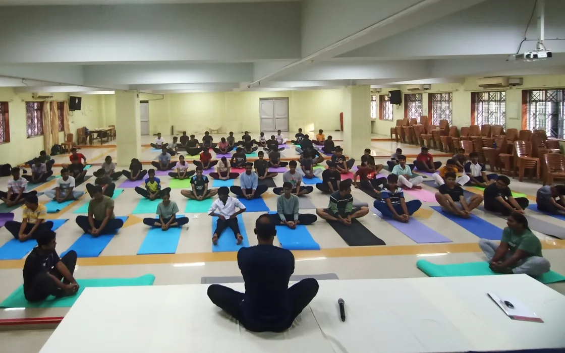 Abhilash seated facing a hall of hospitality students on mats at IHMCT.