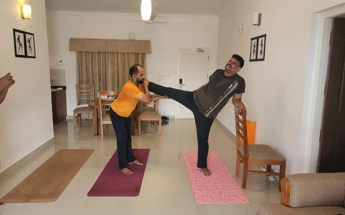 Abhilash steadying a student in a standing balance during a practice in Munnar.