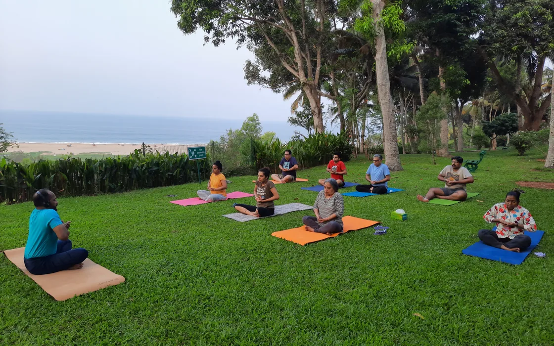 The retreat group seated on mats on the lawn with the sea behind them.