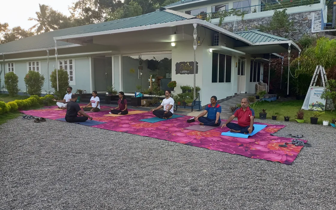 The retreat group seated on a spread of pink mats outside the retreat house at sunrise.